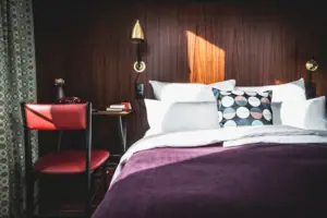 HENRI Düsseldorf Ein Bett mit Kissen und einem Schreibtisch in einem Zimmer.