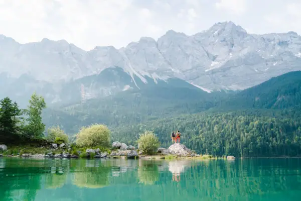 See bei Garmisch-Partenkirchen Menschen stehen auf einem Felsen vor einem See.