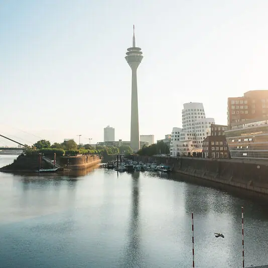 Rhein und Medienhafen Wasser neben einer Stadt mit Gebäuden und einem Turm im Hintergrund.