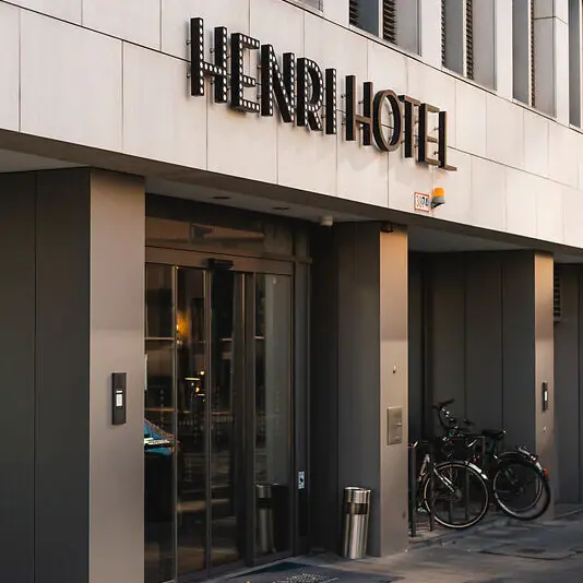 Eingang HENRI Hotel Düsseldorf Ein Gebäude mit einem Schild darauf.