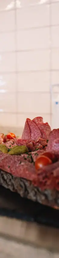 Lecker und regional Rustic wooden platter with a variety of sliced cured meats, presented on a wooden table alongside bread and cutlery.