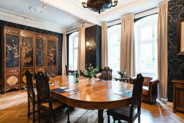 Herrenzimmer im HENRI Berlin Ovaler Tisch mit Holzstühlen mit hoher Lehne