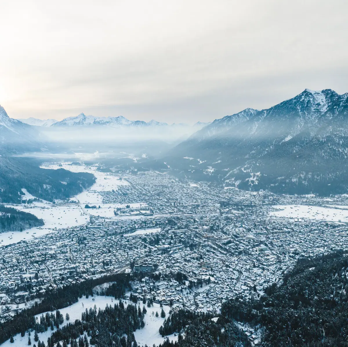 Garmisch-Partenkirchen im Winter Eine verschneite Stadt mit Bergen im Hintergrund.