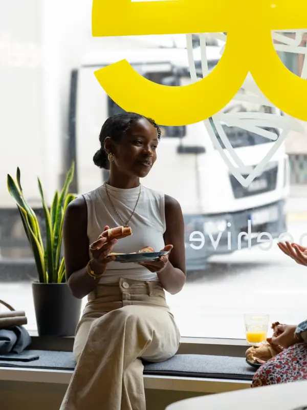 Beehive Düsseldorf Eine Frau sitzt auf einem Fenstersims und isst.