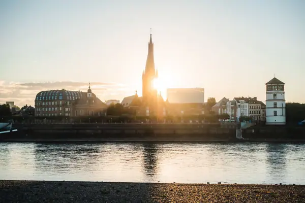 Wasserfläche mit Gebäuden und einem Turm im Hintergrund.