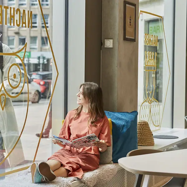 Beehive Düsseldorf Eine Frau sitzt auf einer Fensterbank.