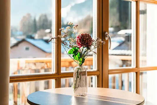 Aussicht Ein Blumenstrauß in einer Vase auf einem Tisch neben einem Fenster.