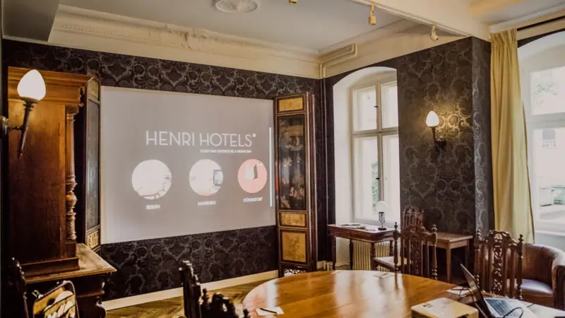 HENRI Herrenzimmer Ein Zimmer mit einer Projektionsleinwand und Holzmöbeln.