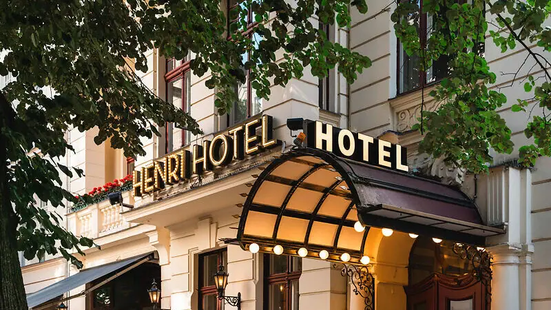 HENRI Hotels Hotelgebäude mit beleuchteter Fassade und Fenstern.