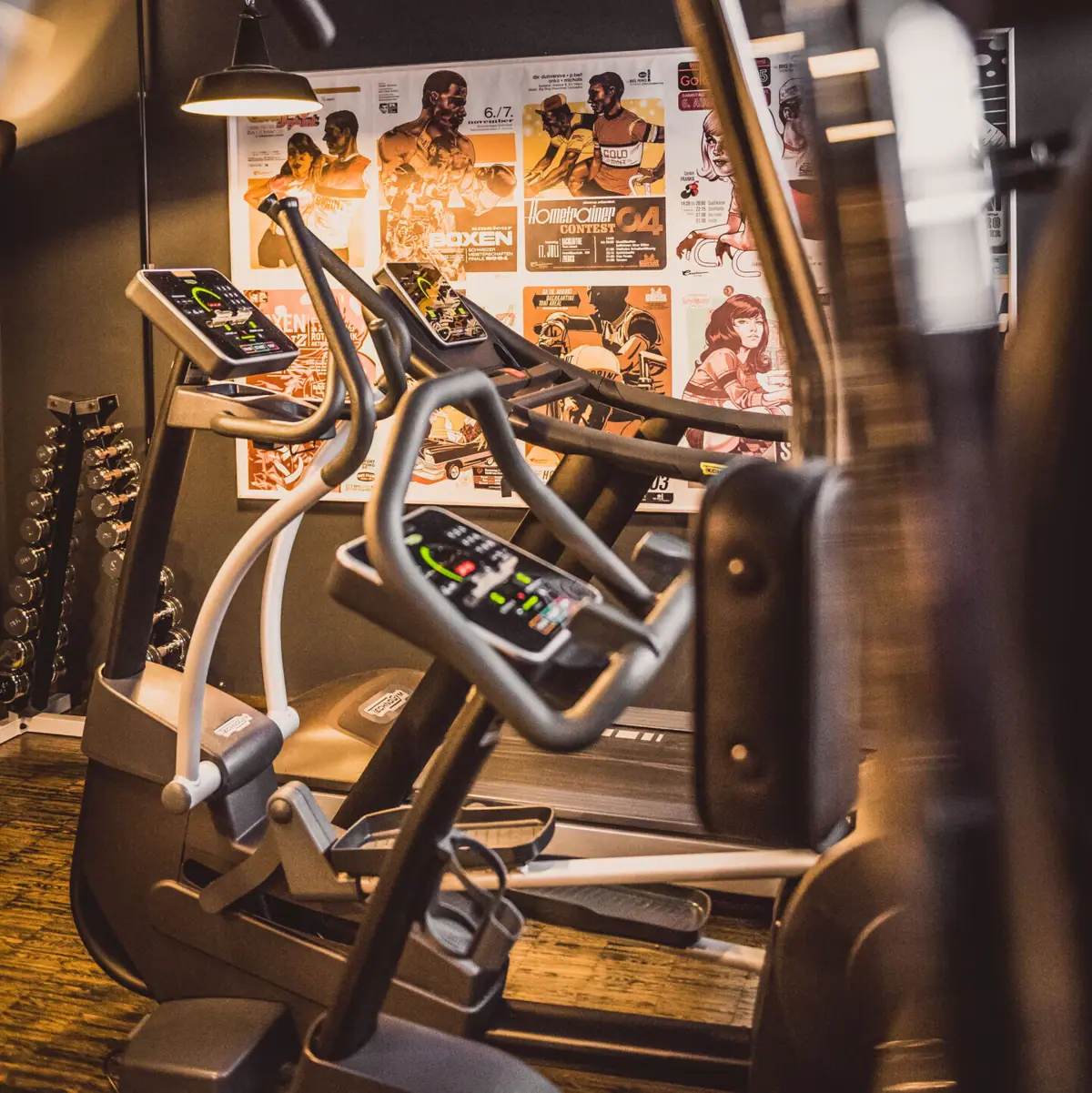 Fitnessraum im HENRI Hotel Hamburg Rau, mit Fitnessgeräten und Hanteln.