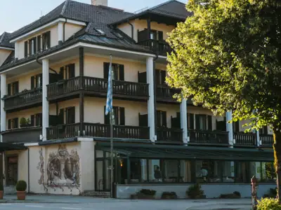 *Eröffnung im Sommer 2026* Ab 89 € pro Person im Doppelzimmer mit Frühstück und Nachmittagsjause. Sonnenuntergang über einem Gewässer, umgeben von Bäumen und Gras.