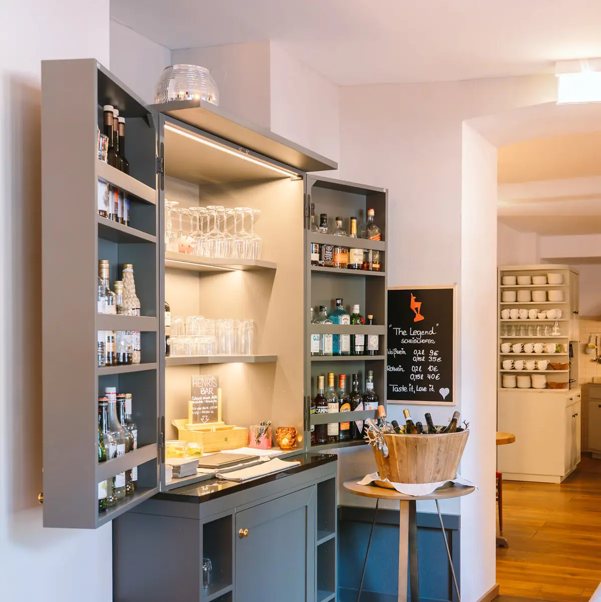 Bar Ein Raum mit einem Schrank und Regalen mit Flaschen und Gläsern.