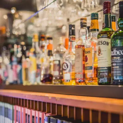 Bar im HENRI Hotel Hamburg Ein Regal mit Flaschen alkoholischer Getränke.