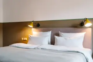 Bett Ein Bett mit weißen Kissen und einer Lampe.