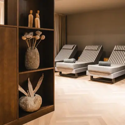 Entspannungsraum im HENRI Hotel Kitzbühel Ein Raum mit einem Regal und Stühlen.