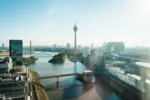 Düsseldorf Ein Fluss mit einer Brücke und einer Stadt mit einem Turm.