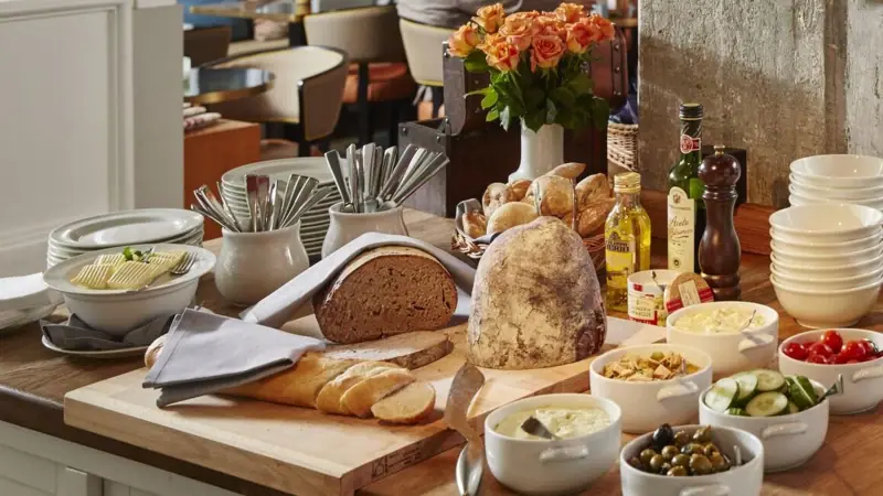 Abendbrot im HENRI Auf einem Tisch liegt ein Schneidebrett mit Brot sowie einige Schälchen mit Speisen.