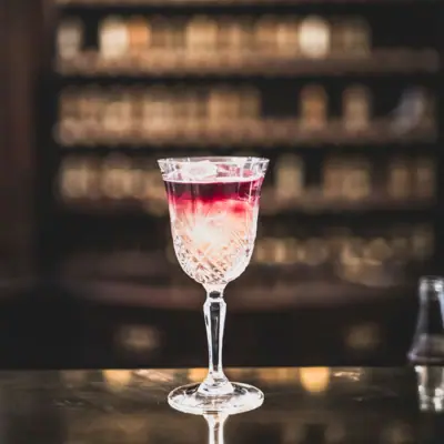HENRI Berlin Drinks Ein Glas mit Getränk auf einer Bar.