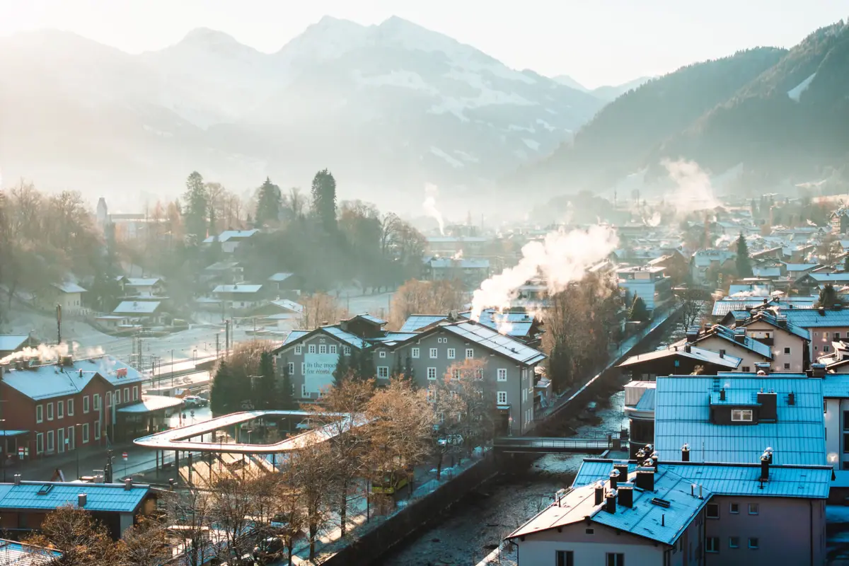Winterlandschaft mit schneebedeckten Dächern und Bergen im Hintergrund