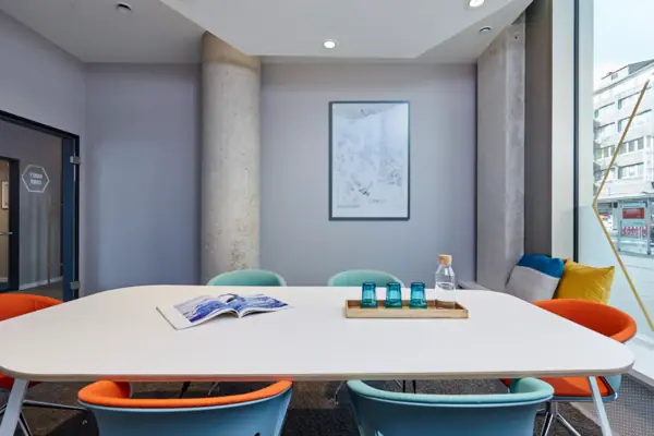 Beehive Düsseldorf Ein Tisch mit blauen Stühlen und einem Buch darauf.