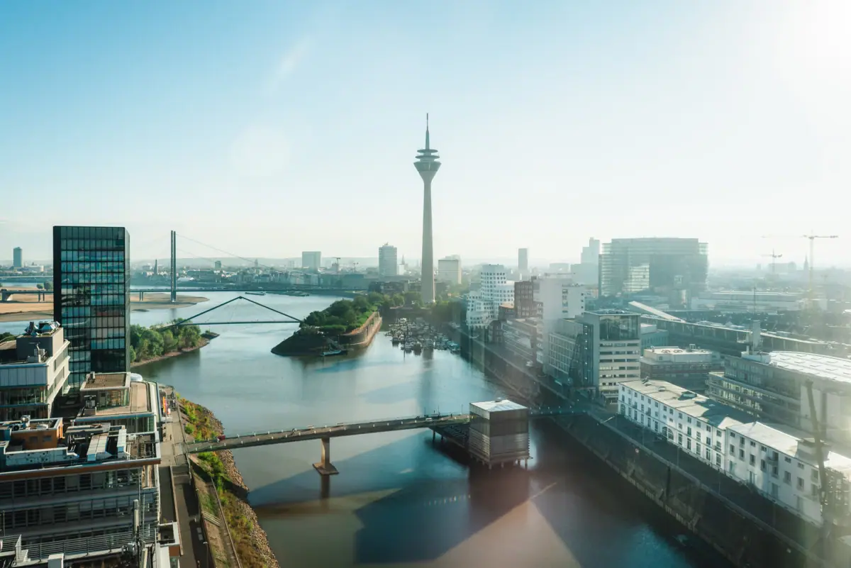 Düsseldorf Fluss mit Brücke und Stadt im Hintergrund, dominiert von einem Turm.