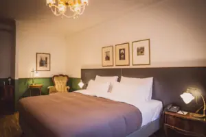 Zimmeransicht Ein Bett mit einem Kronleuchter und Bildern an der Wand.