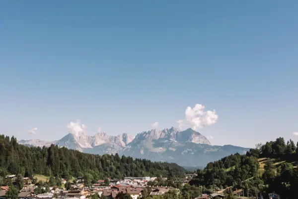 Kitzbühler Alpen Eine Stadt in den Bergen mit Bäumen und klarem Himmel.