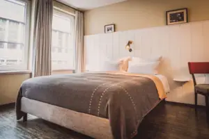 Bett Bett mit Lampe und Fenster im stilvollen Hotelzimmer.