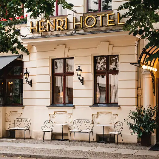 HENRI Hotel Berlin Ein Gebäude mit Stühlen und einem Schild.