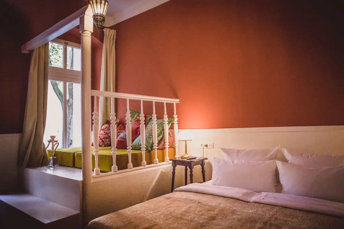 HENRI Berlin Orient Zimmer Ein Bett mit Kissen und einer Lampe in einem Zimmer.