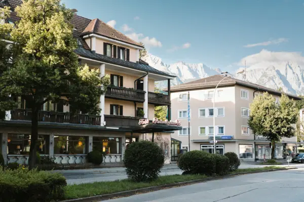 Garmisch-Partenkirchen Ein Gebäude mit Bäumen und Büschen am Straßenrand.