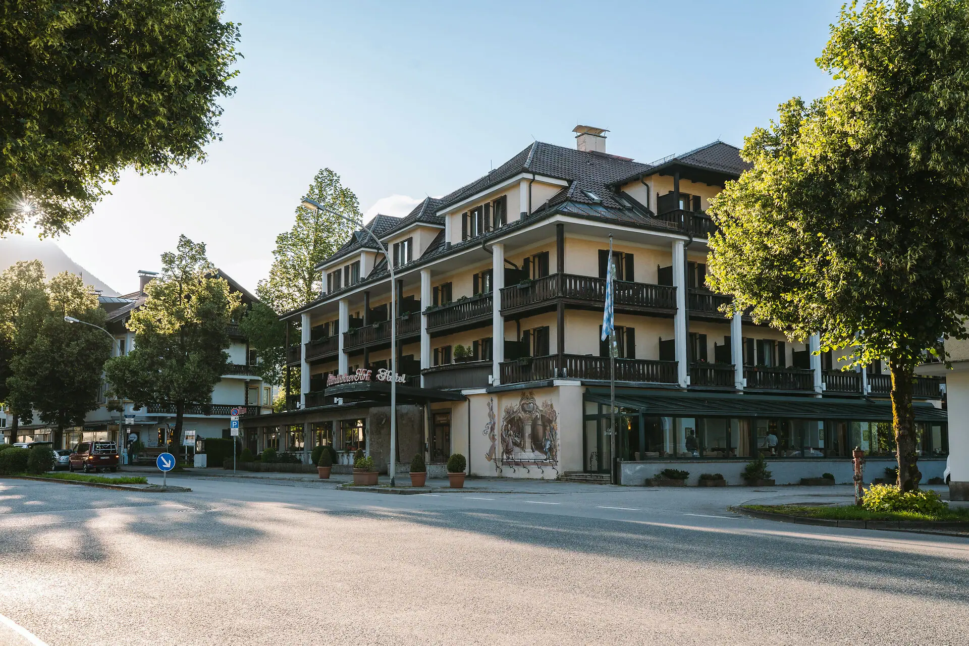 Außenansicht HENRI Hotel Garmisch-Partenkirchen Die Außenansicht vom HENRI Hotel Garmisch-Partenkirchen mit Bäumen und einer Straße.