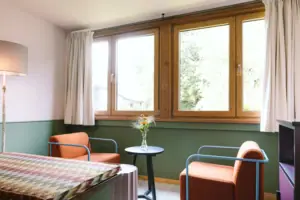 Hotelzimmer im HENRI Hotel Garmisch-Partenkirchen Eine Sitzecke mit zwei Sesseln vor einem Fenster in dem Hotelzimmer Chambre im HENRI Hotel Garmisch-Partenkirchen.