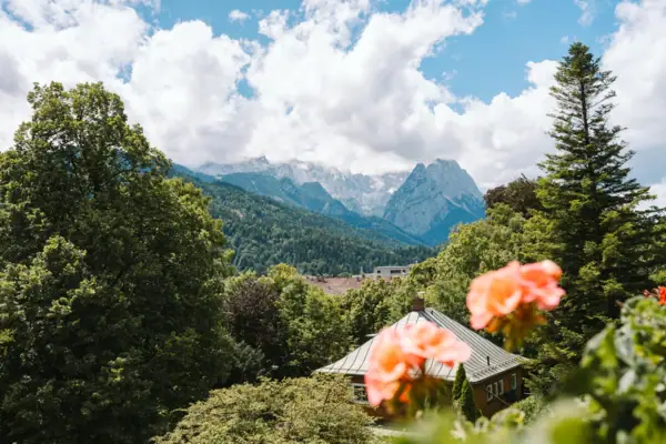 Ausblick HENRI Garmisch-Partenkirchen Ausblick vom Balkon aus dem HENRI Hotel Garmisch-Partenkirchen mit Blumen und Bergen im Hintergrund.