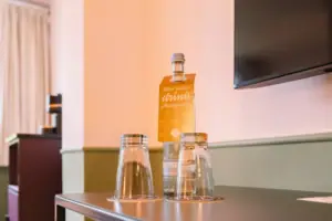 Hotelzimmer Chambre im HENRI Hotel Garmisch-Partenkirchen Eine Flasche und Gläser auf einem Tisch.