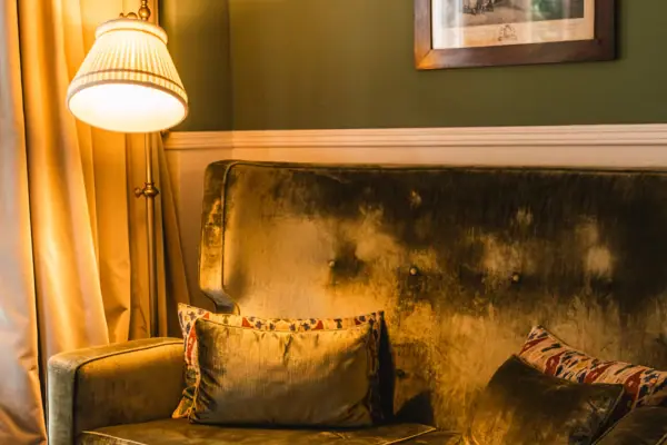 HENRI Berlin Zimmer Couch Ein Sofa mit Kissen und einer Lampe in einem Raum.