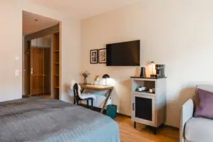 L-Studio Haus Ache HENRI Hotel Kitzbühel Schlafzimmer mit Bett, Schreibtisch und Fernseher.