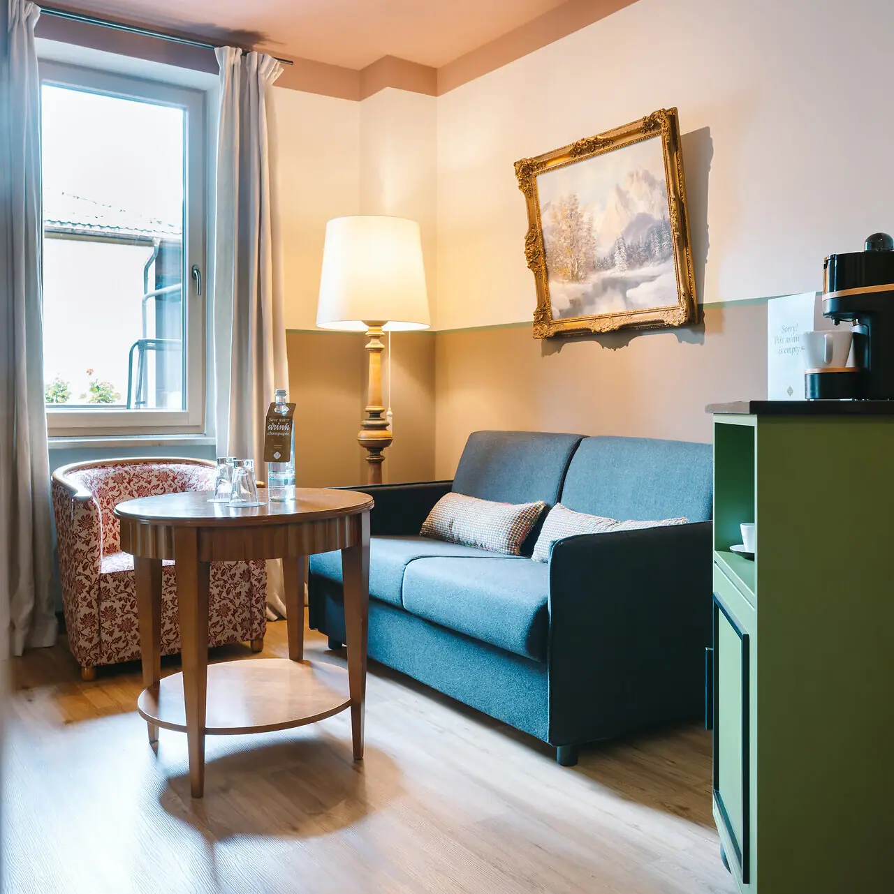 Hotelzimmer im HENRI Garmisch-Partenkirchen Wohnbereich in einem Hotelzimmer im HENRI Garmisch-Partenkirchen mit einem Sofa und einem Tisch.