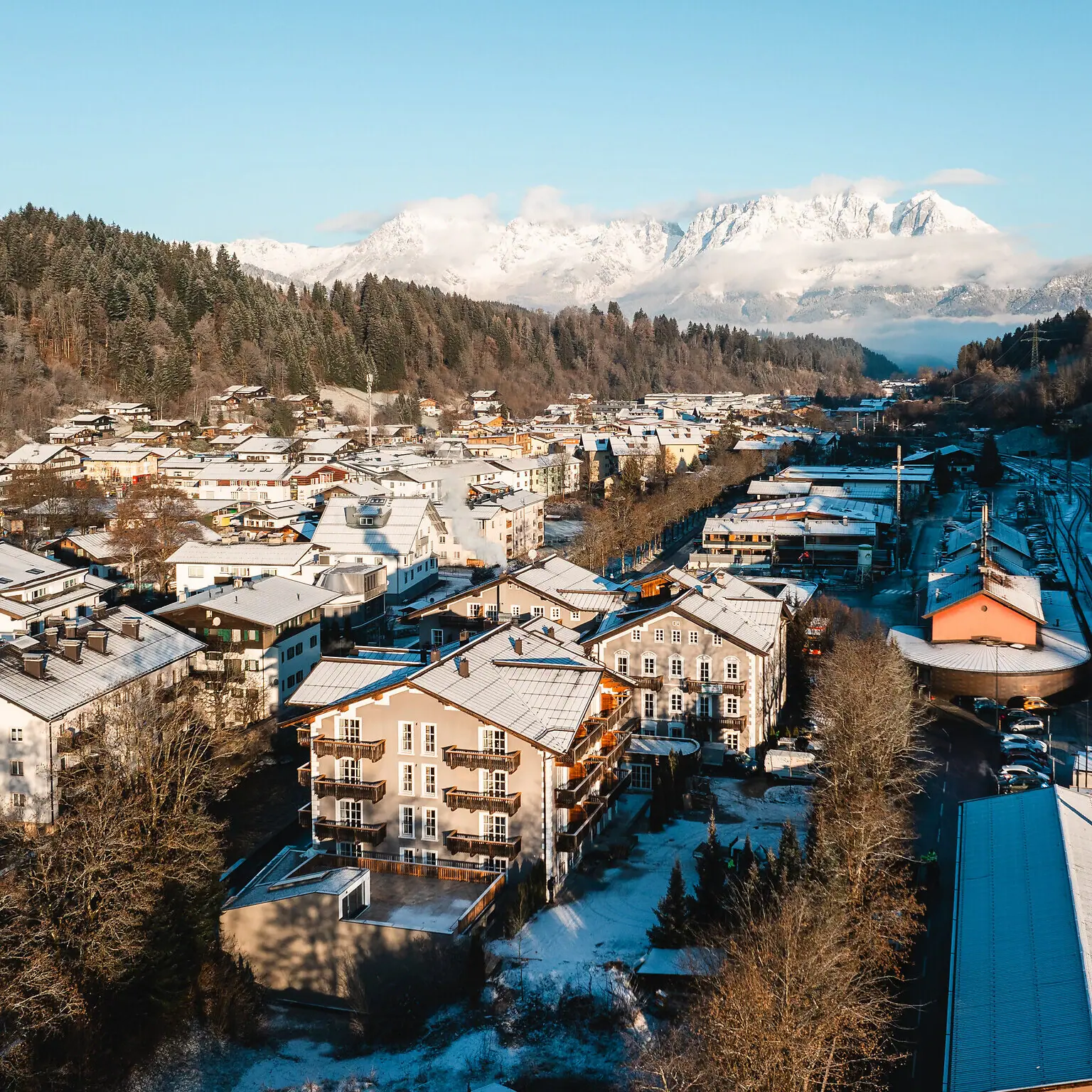 HENRI Hotel Kitzbühel Verschneite Stadt im Winter mit Häusern im Hintergrund.