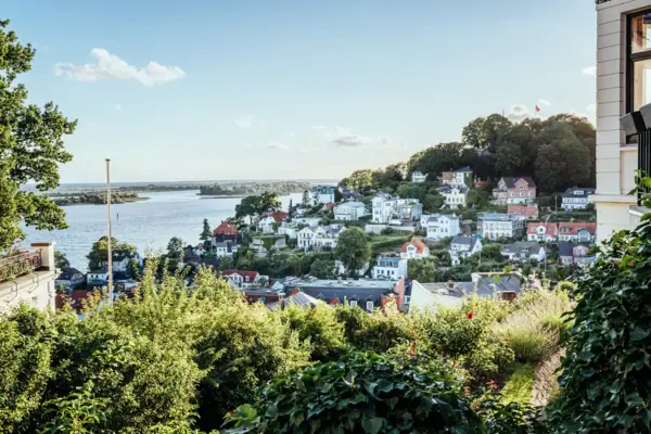 Treppenviertel Stadtansicht mit Wasserfläche im Vordergrund, umgeben von Gebäuden und Bäumen unter einem bewölkten Himmel.