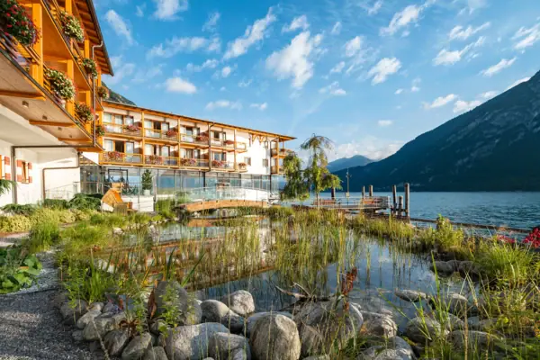 aja Fürstenhaus am Achensee das aja Fürstenhaus am Achensee mit einem Teich und Bergen im Hintergrund.