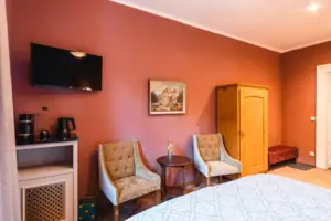 Zimmeransicht Ein Zimmer mit einem Bett, zwei Stühlen und stilvoller Inneneinrichtung.