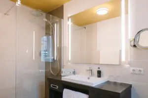 Badezimmer im HENRI Hotel Garmisch-Partenkirchen Ein Badezimmer mit Waschbecken und Spiegel im HENRI Hotel Garmisch-Partenkirchen.