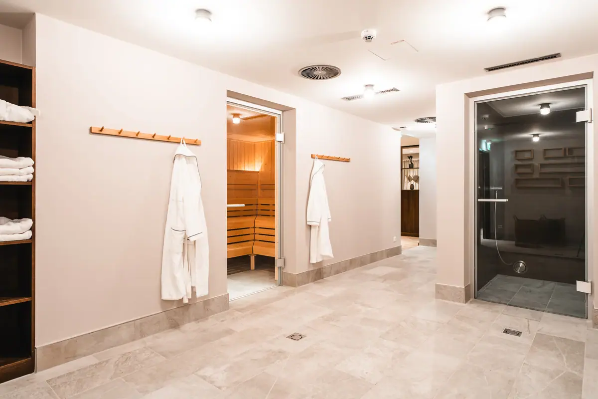 Sauna-Bereich HENRI Kitzbühel Ein Raum mit weißen Bademänteln und einer Sauna.
