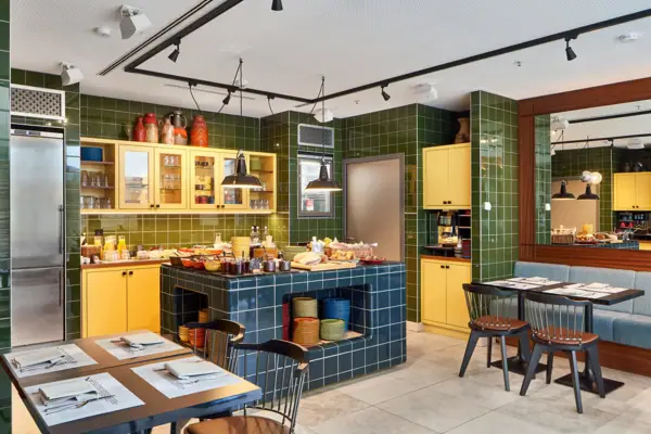 HENRI Düsseldorf Ein Raum mit grünen Fliesen und gelben Schränken.