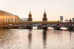 Oberbaumbruecke-Berlin-Spree-Sonnenuntergang Ansicht der backsteingotischen Oberbaumbrücke in Berlin bei Sonnenuntergang mit einer gelben U-Bahn und Spiegelung im Wasser.