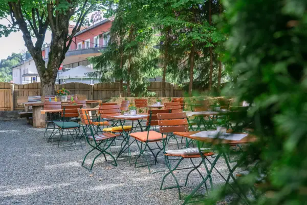 Biergarten im HENRI Kitzbühel Eine Gruppe von Tischen und Stühlen im Freien.