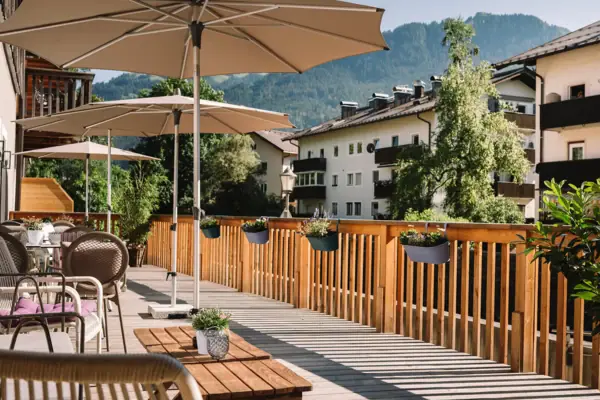 Terrasse im HENRI Kitzbühel Eine Terrasse mit Stühlen und Sonnenschirmen auf einem Deck.