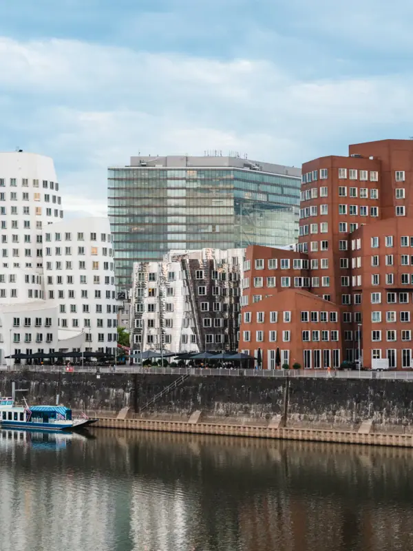 Düsseldorf Ein Fluss mit Booten und Gebäuden im Hintergrund.