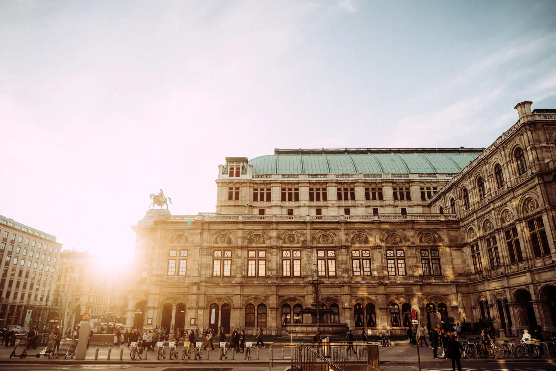 Gebäude Wien Ein großes Gebäude mit Menschen, die auf dem Gehweg spazieren.